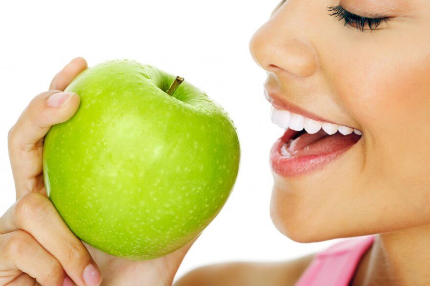 woman eating an apple after getting Dental Implants in North Miami