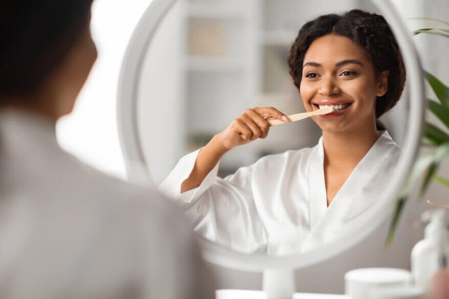 woman brushing her teeth after visiting her aventura dentist